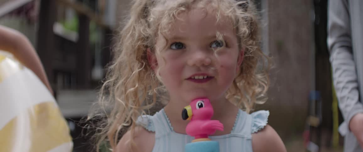 The girl is smiling while holding her toy