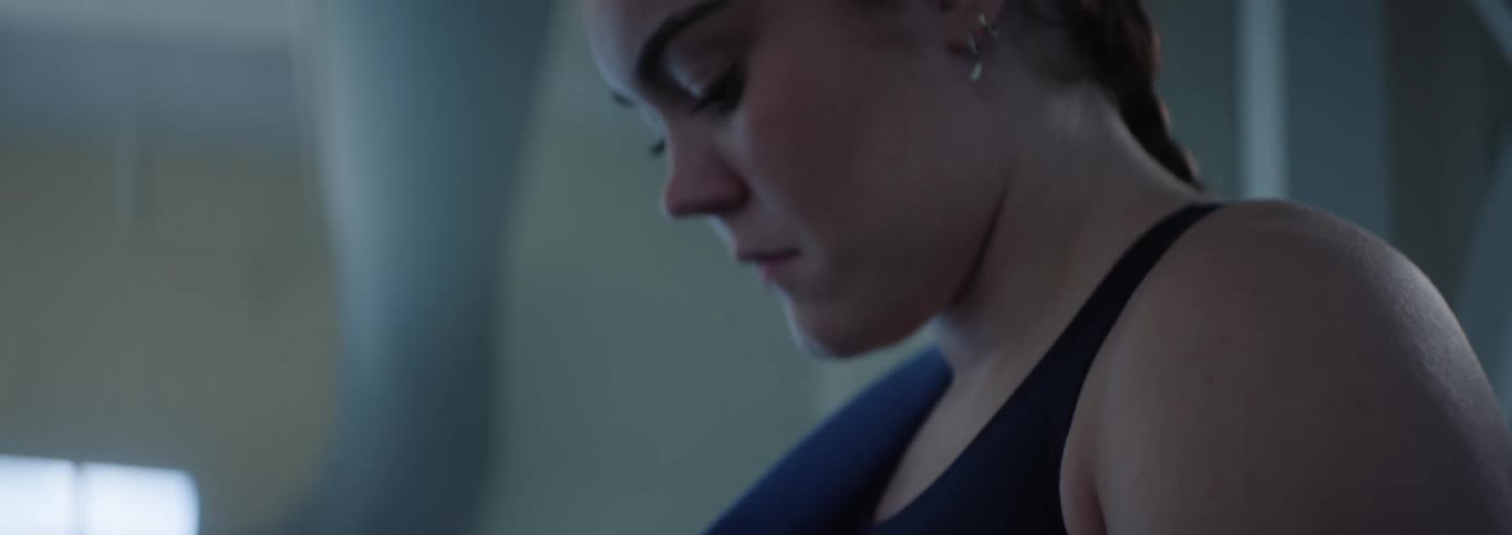 The video shows a swimmer seen from the waist up adjusting black wristbands a speedo logo is visible on her dark swimsuit