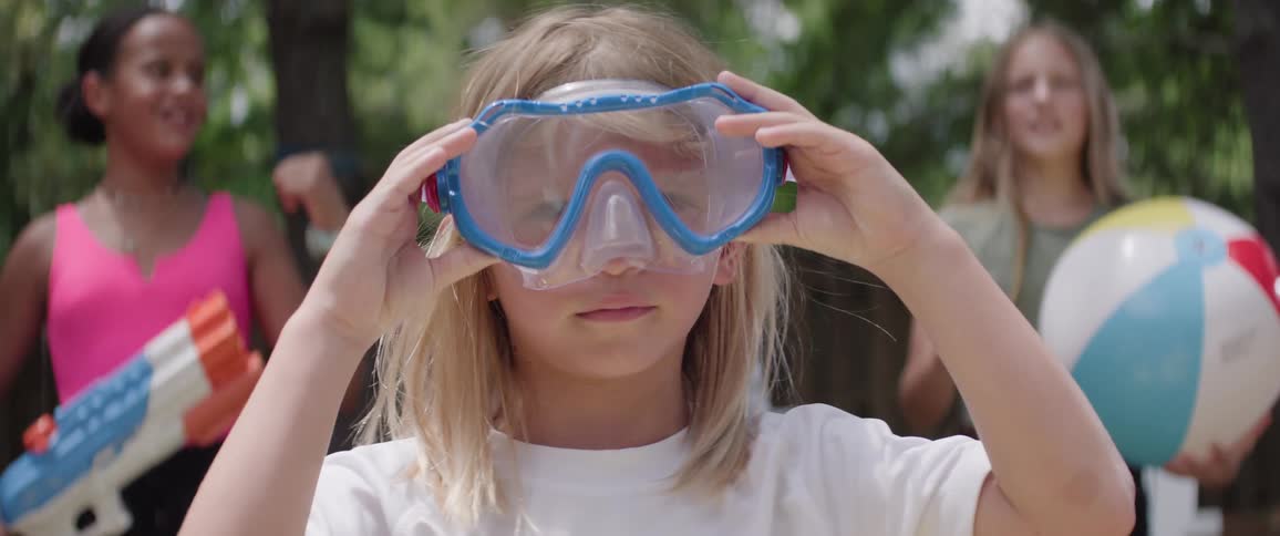 A girl puts on goggles as girls behind her chant