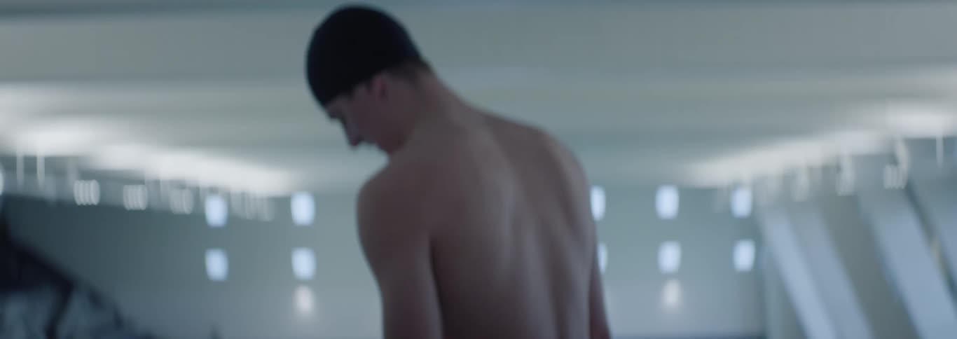 Man with swimming cap indoors taking deep breaths in concentration