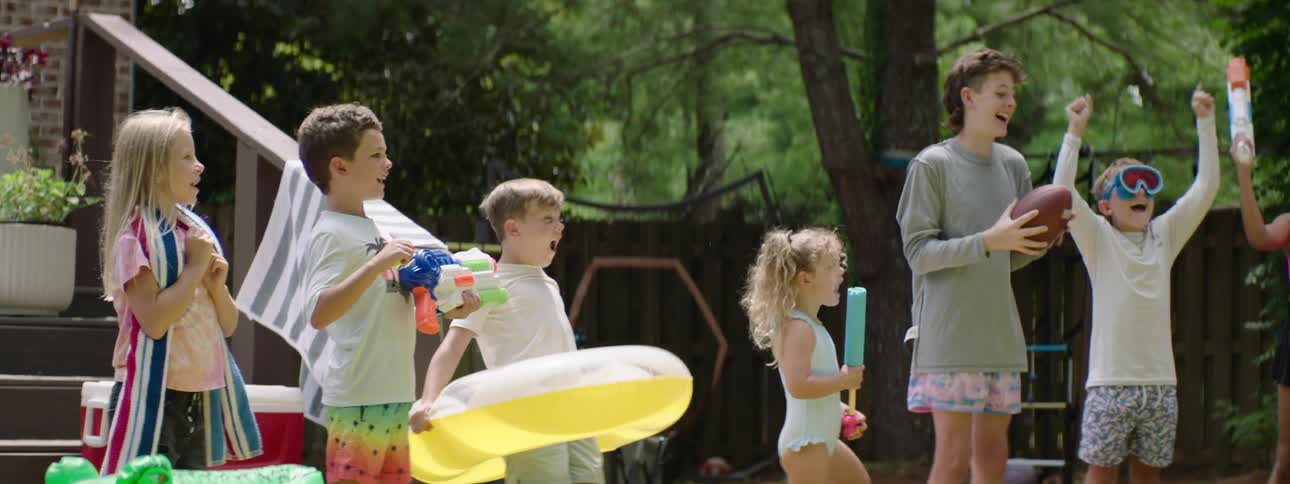 Group of children holding toys in a backyard during the day