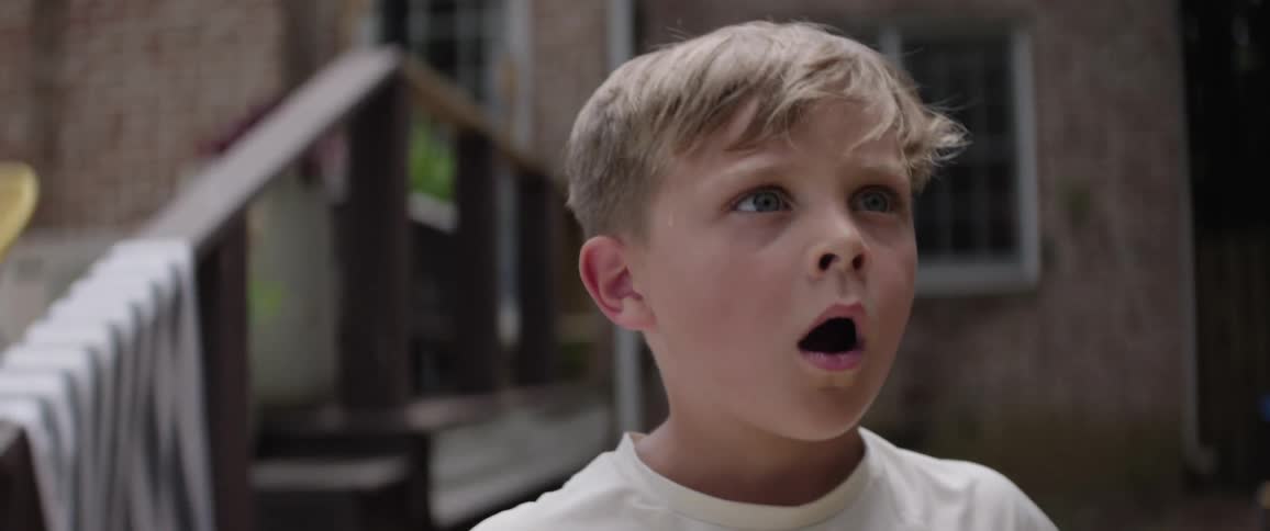 Boy in a backyard opening his mouth in surprise