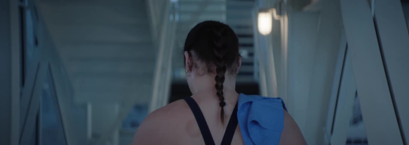 Woman with braided hair and a swimsuit walking up the stairs