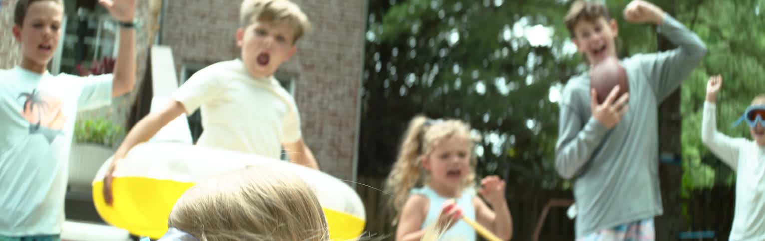 Little girl running on a tarp and falling on the ground and her friends cheering happily around