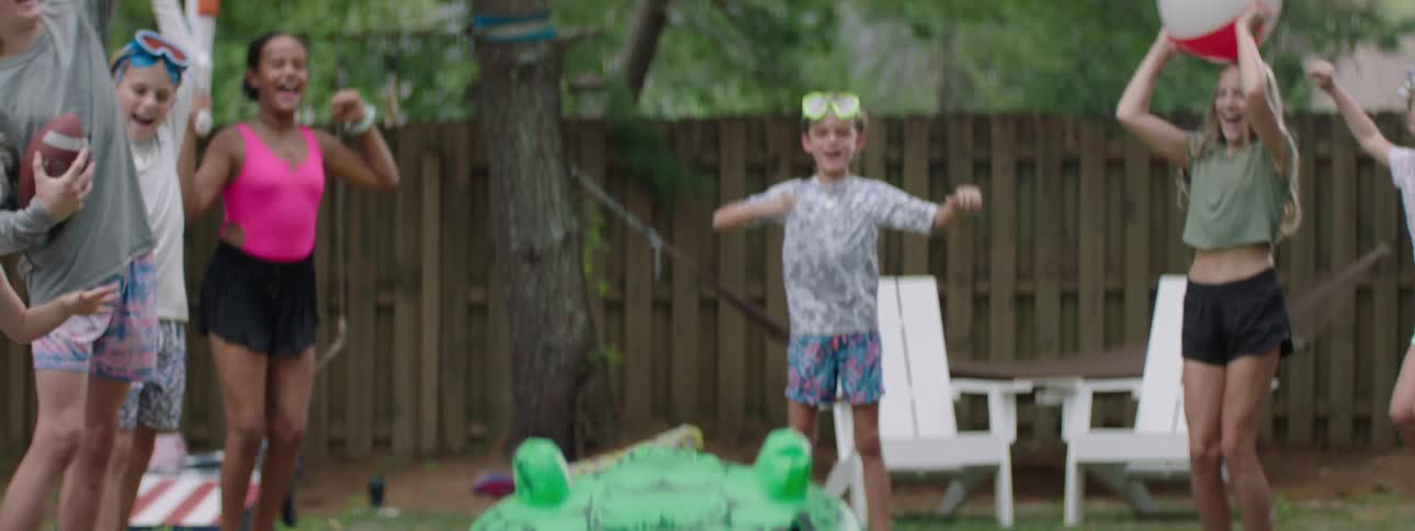The video features three children outdoors on a sunny day with two boys wearing goggles and a girl in a pink top they all raise their fists in excitement suggesting they are playing or celebrating