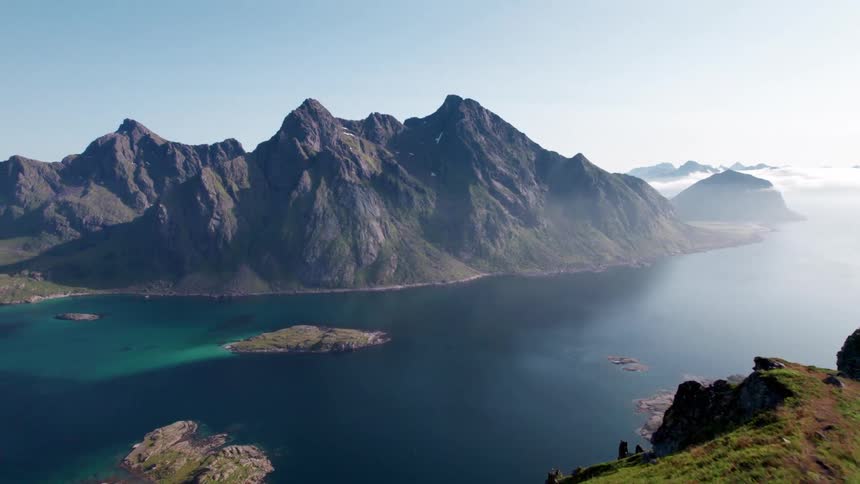 The video displays a stunning aerial view of a mountainous coastal landscape with clear deep blue and turquoise waters