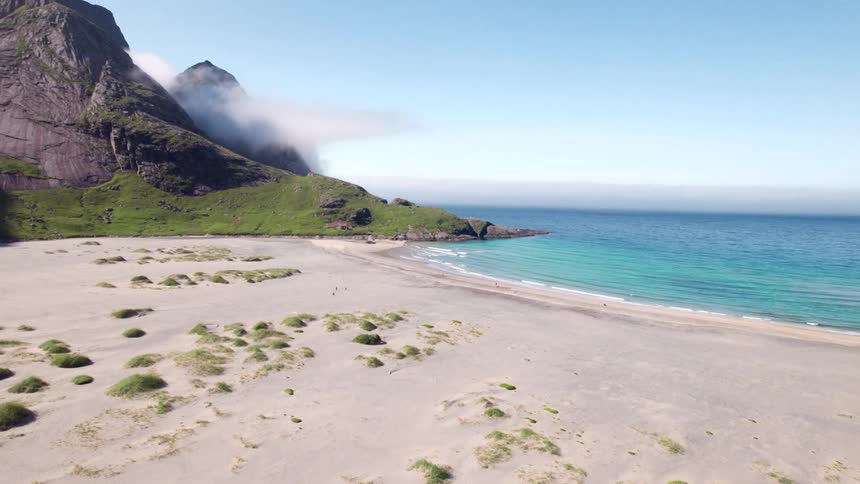 Landscape of a beach with turquoise blue waters and the mountainous coastline in the background