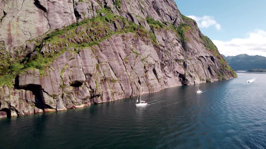 The small sailboats travel around the mountains