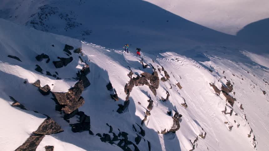 Two people climbing a steep slope of a snowcovered mountain