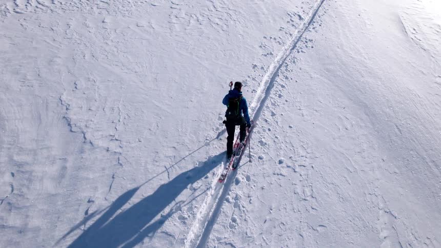 The man hikes up the mountain on skis