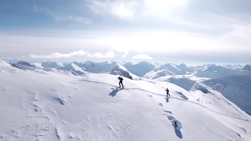 Men climbing up the steep mountain on snow skis