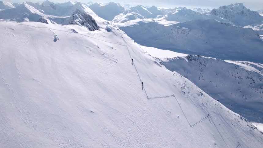 Two people hike up a snowcovered mountain at midday