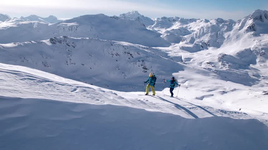 The two people are climbing the mountain to ski down
