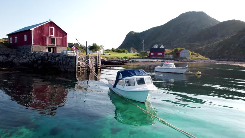 The boat is anchored by the barn near the pier