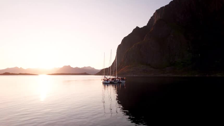 Three boats docked near a large cliff face