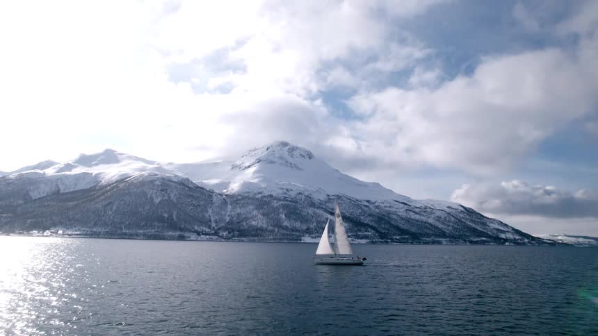 A boat sailing past some snowy mountains