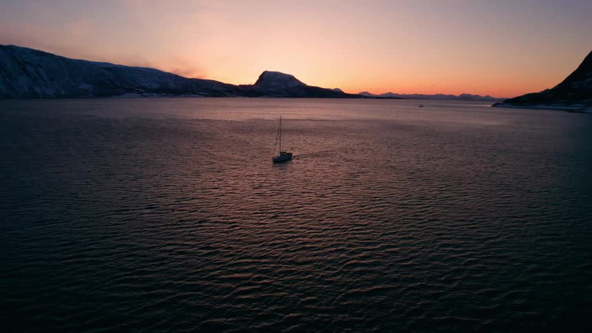 Solitary boat floats on calm fjord waters at sunset