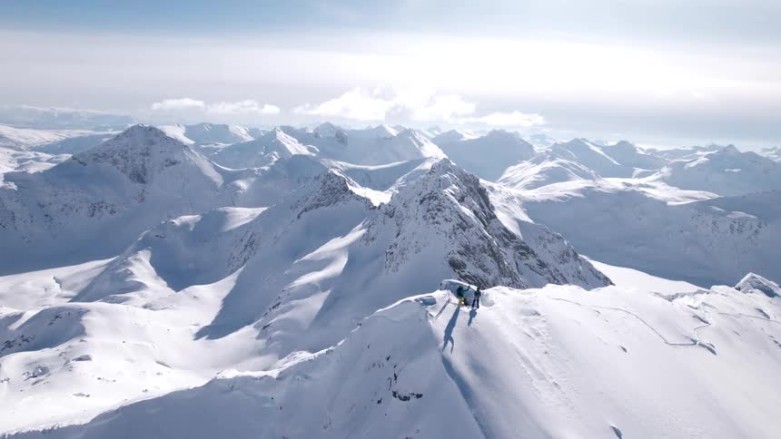 Two people on a mountain peak surrounded by snow