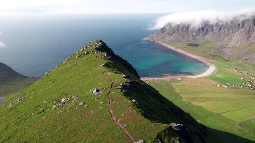 Small group of people walking on a mountain cliff with the sea in the background