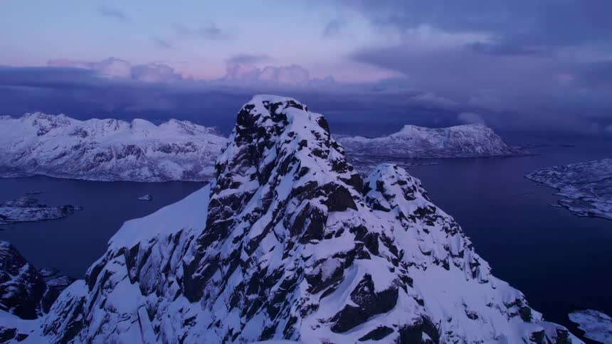 Aerial landscape of a mountain with a steep snowcapped peak and surrounded by the sea