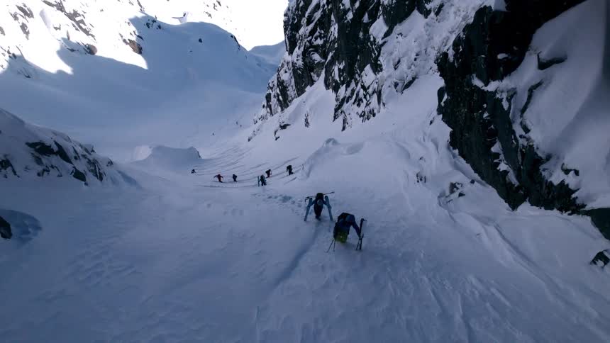 People with snowboarding equipment climbing a snowy mountain