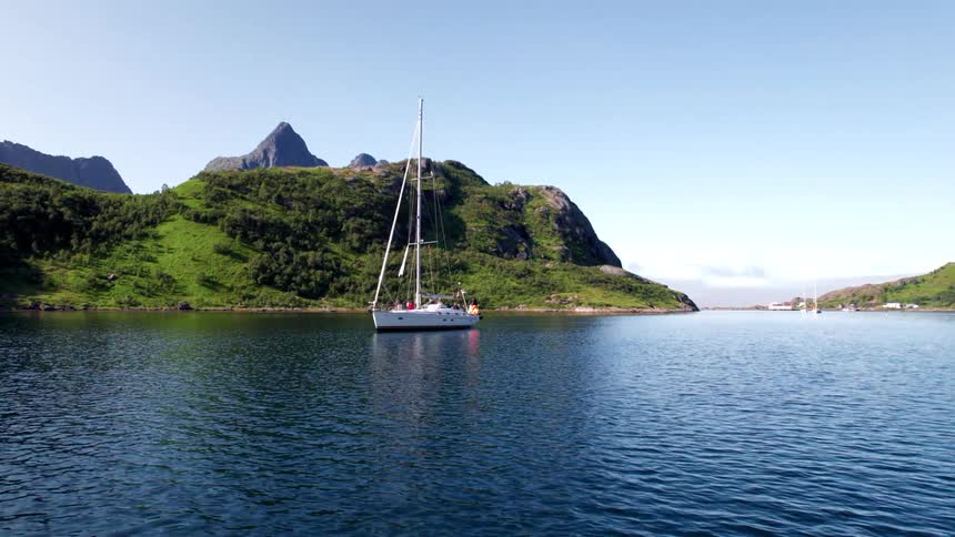 The sailboat is in the blue water by the green island