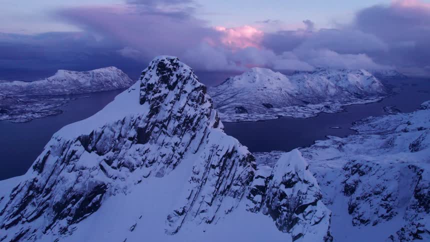 Icy fjords and snow covered peaks glow beneath a dusk sky