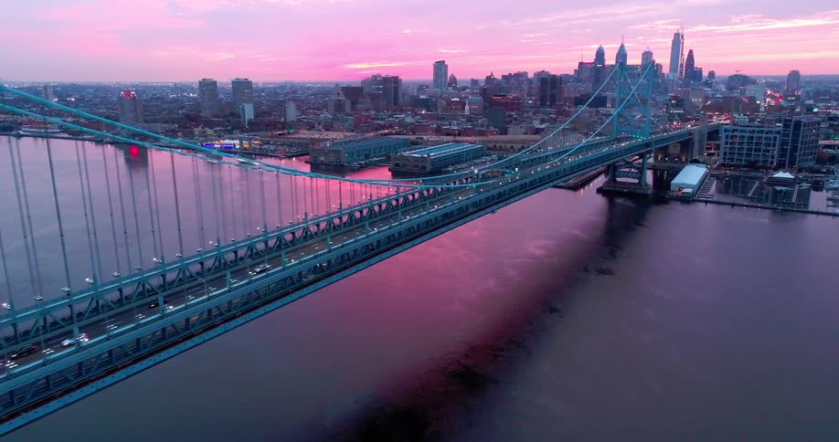 A lone bridge leading into a city at dawn