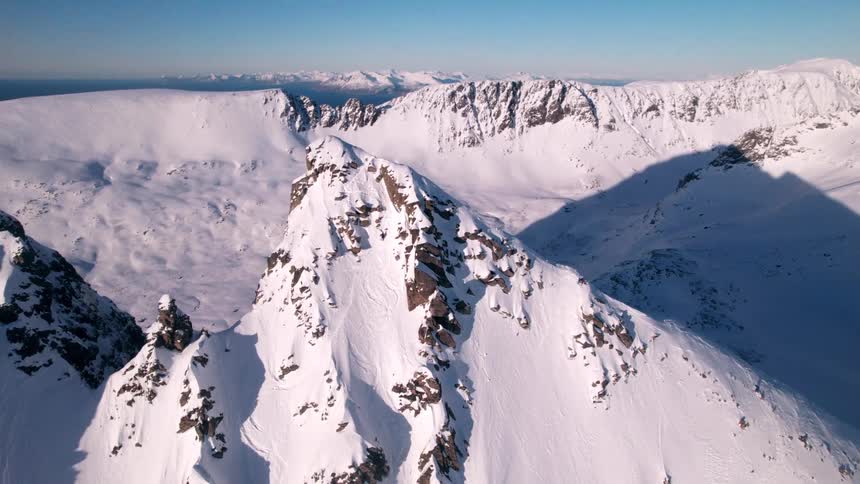 Aerial landscape of snowcapped mountains against a clear blue sky