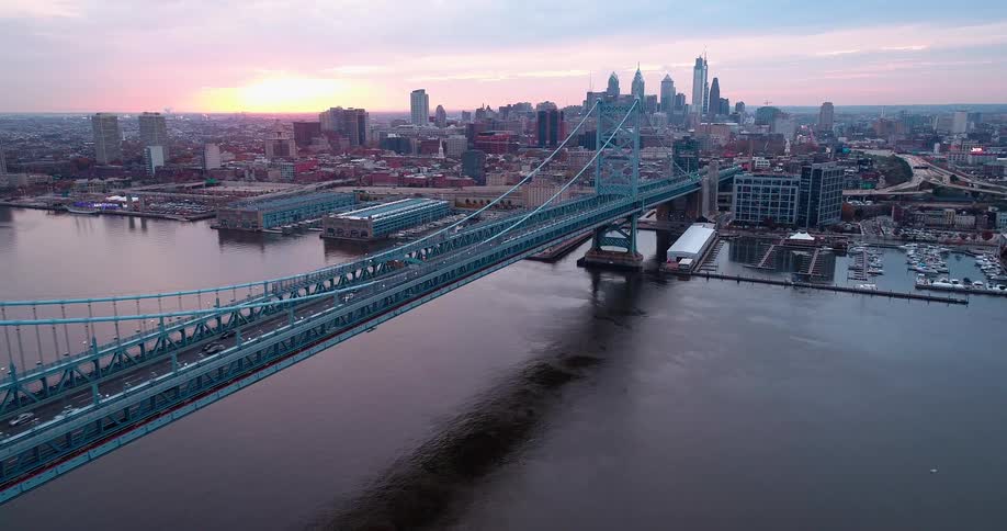 Suspension bridge meets city skyline at sunrise