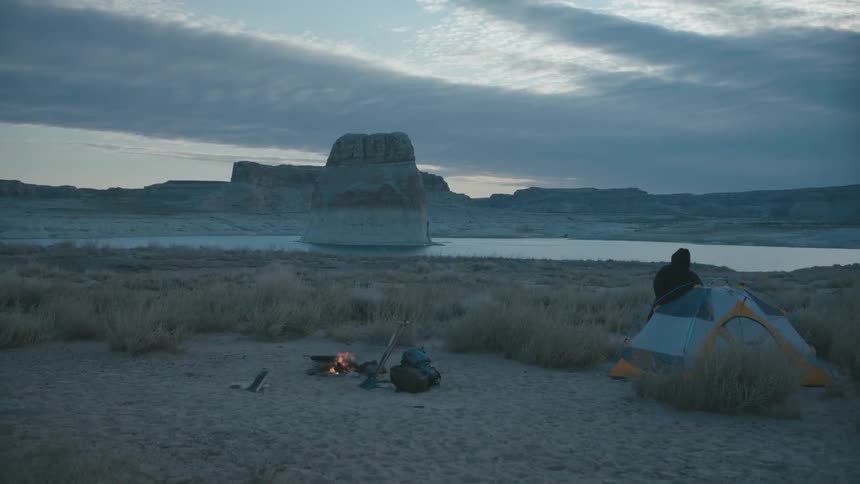 Camper gets out of the tent to the campfire by the lake