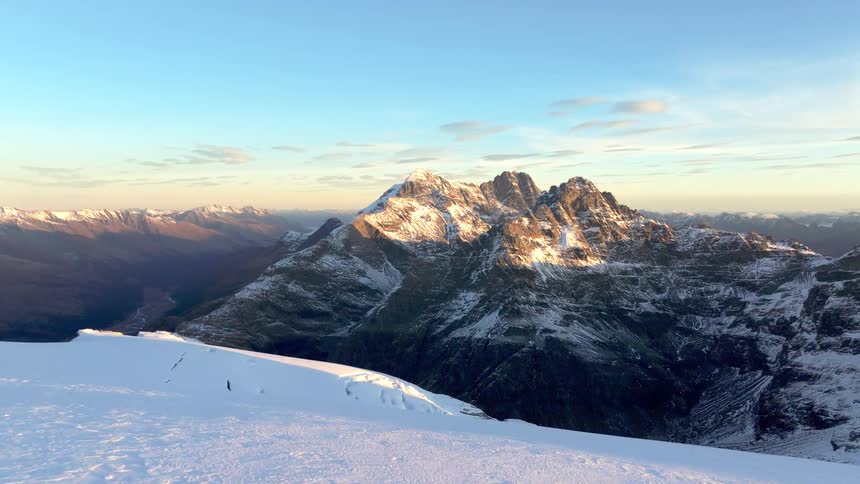 Snowy mountain peaks glow under warm sunset light