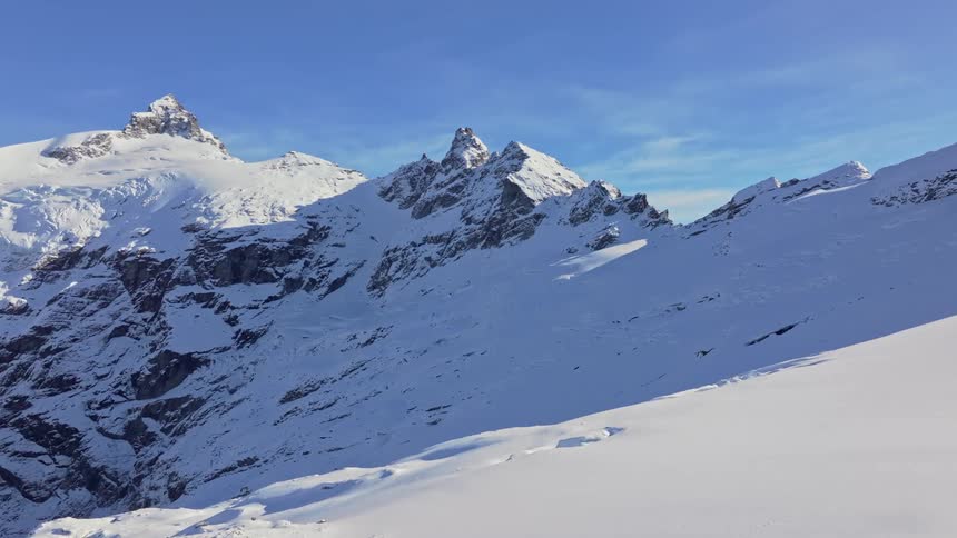 Shadows cover a portion of a snowy mountain on a cloudy winter day