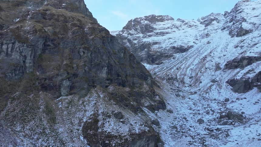 Steep snow covered mountains tower under clear skies