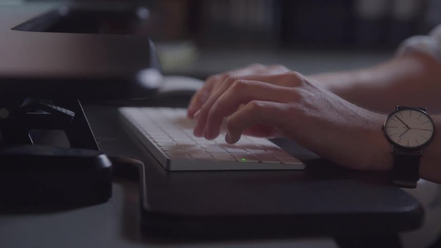 This video offers a closeup shot of a persons hands as they type on a sleek white keyboard with a watch visible on their left wrist the focus on the hands and keyboard suggests an emphasis on work productivity or digital interaction