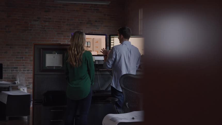 A man and woman review a design displayed on a computer screen