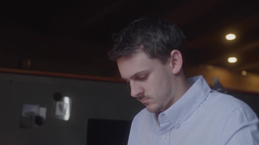 Man standing indoors concentrates while working on a task