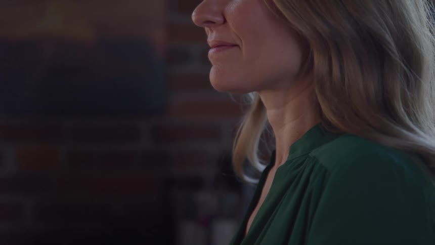 Woman smiles while in a room with a brick wall during the daytime
