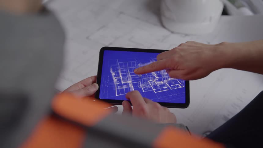 Two people examine a digital 3d architectural blueprint on a tablet actively pointing out structural details