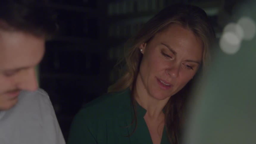 A woman with long blonde hair talks to the man beside her