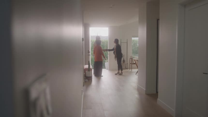 A couple shakes hands with a woman while standing inside a residence