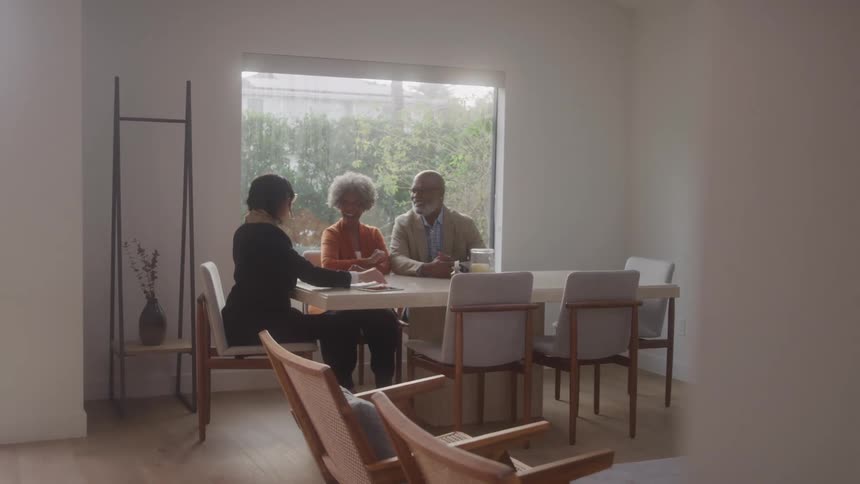 An elderly couple happily shake hands with a female realtor