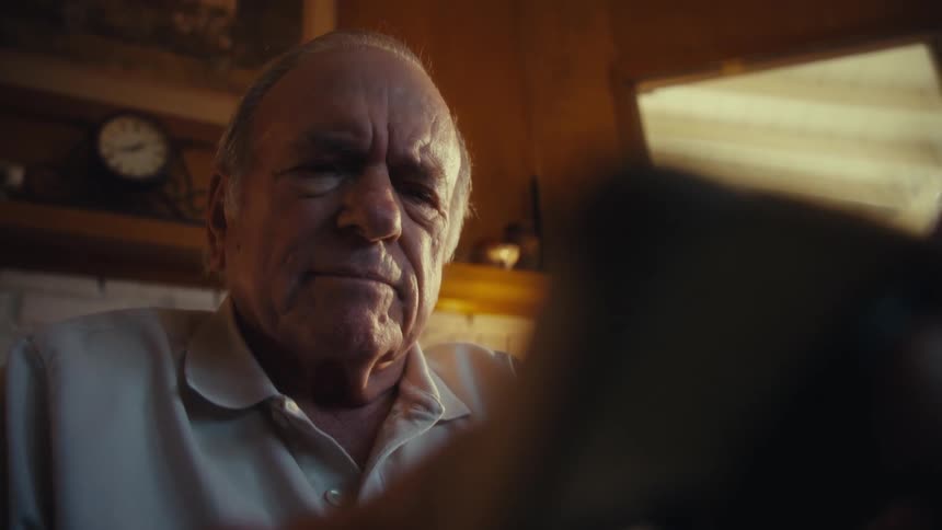 An elderly man using a phone in his living room