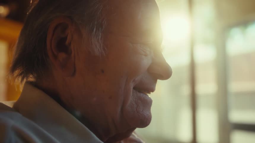 An elderly man laughing in his living room