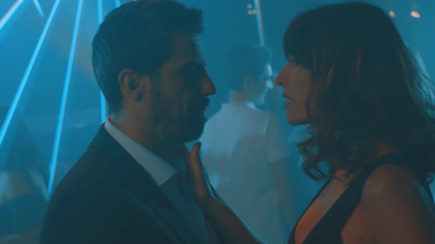 Couple slow dances on the dance floor in a foggy club while light effects shine through the air