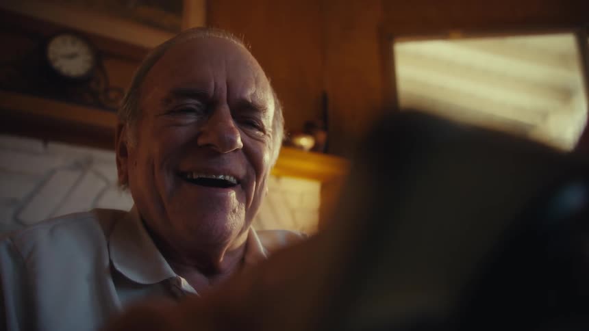 The video features a closeup of an older man with a warm genuine smile and a receding hairline laughing heartily the shot captures his joyful expression in an intimate welllit indoor setting emphasizing the warmth of the moment