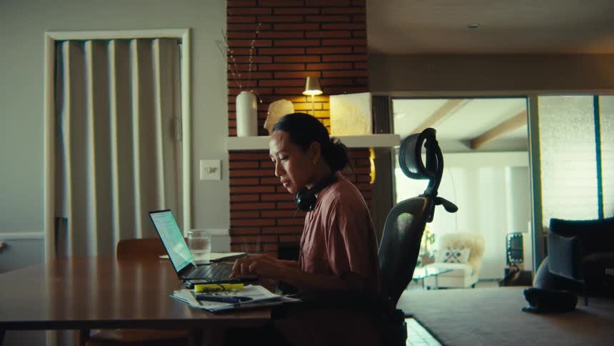 The woman begins laughing while using her laptop