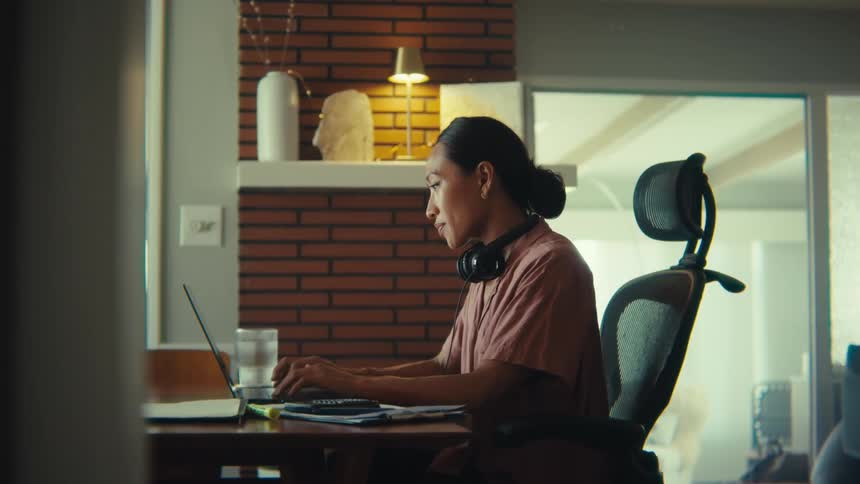 Woman works on her computer while sitting at home during the daytime