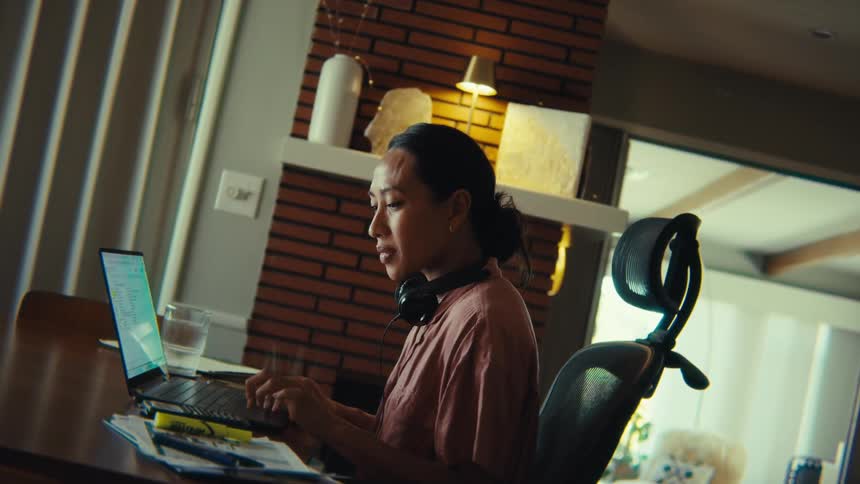 Woman sitting at a table typing on a laptop