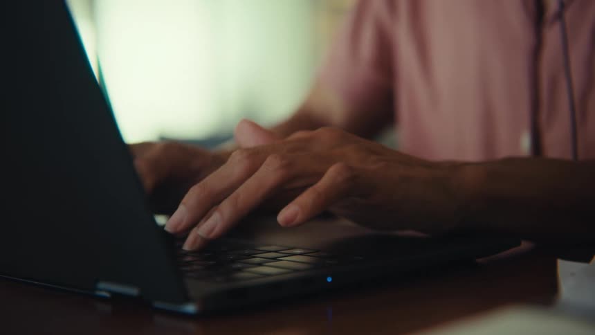 A man wearing headphones typing on a laptop on a table